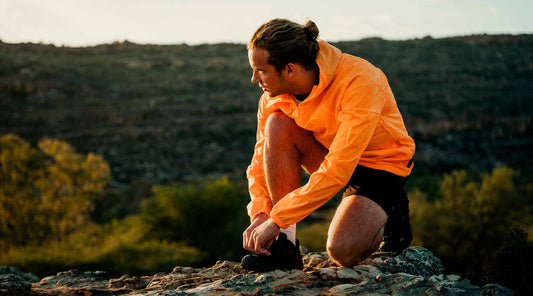 Sporttinen mies solmii kengännauhojaan syksyisessä säässä vuoristossa