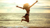 hyväkuntoinen nainen hyppää rannalla bikneissä