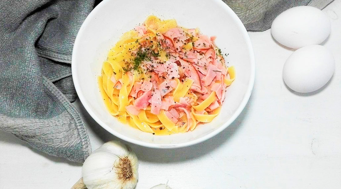 Annoskuva Pasta Carbonarasta. Lautasen vierellä valkosipulia ja kaksi kananmunaa.