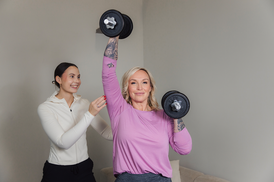 Jutta nostaa käsipainoja, valmentaja vierellä